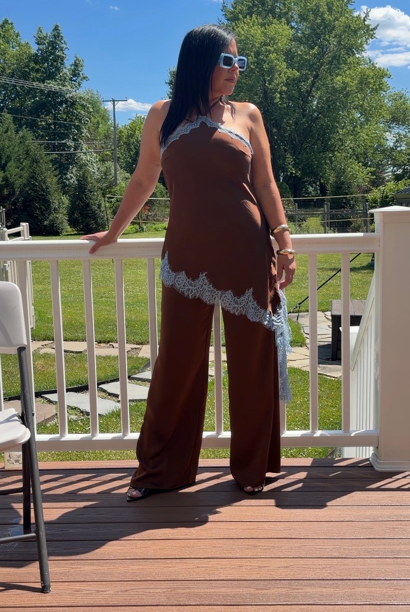 Chocolate brown satin halter jumpsuit with asymmetrical lace trim, front view"