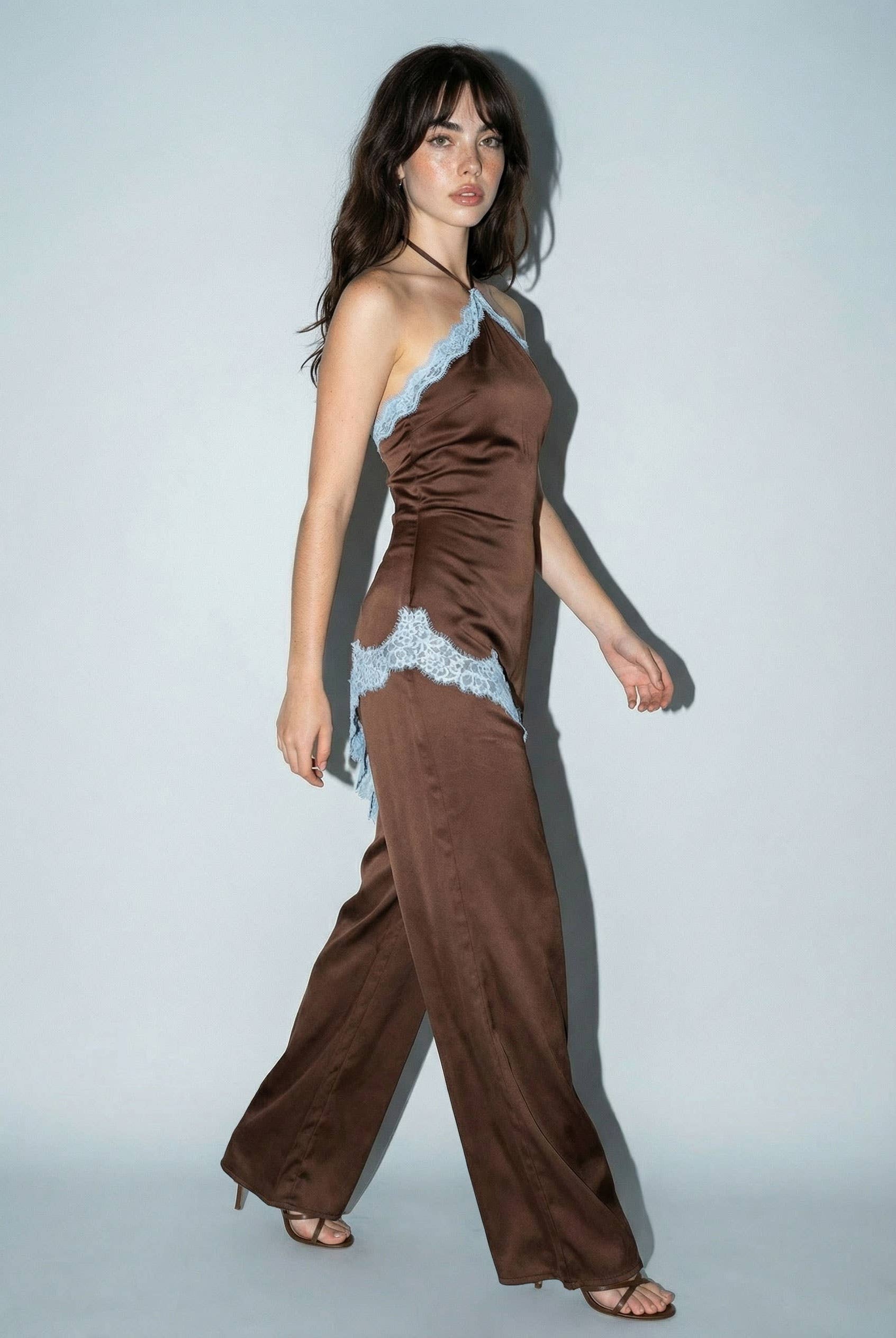 Close-up of asymmetrical lace applique on chocolate brown satin jumpsuit